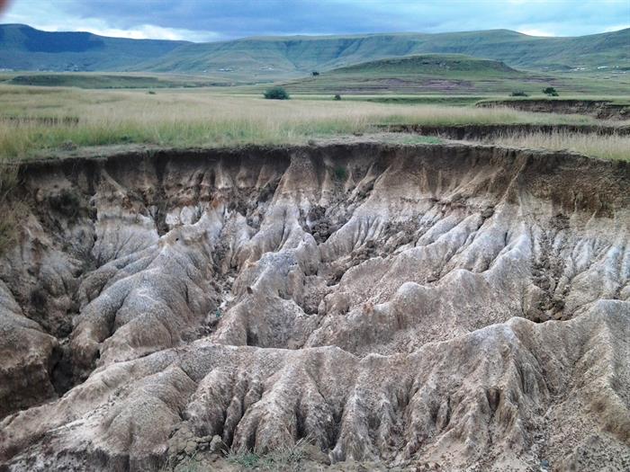 Soil erosion Soil erosion donga with grass and mountains behind